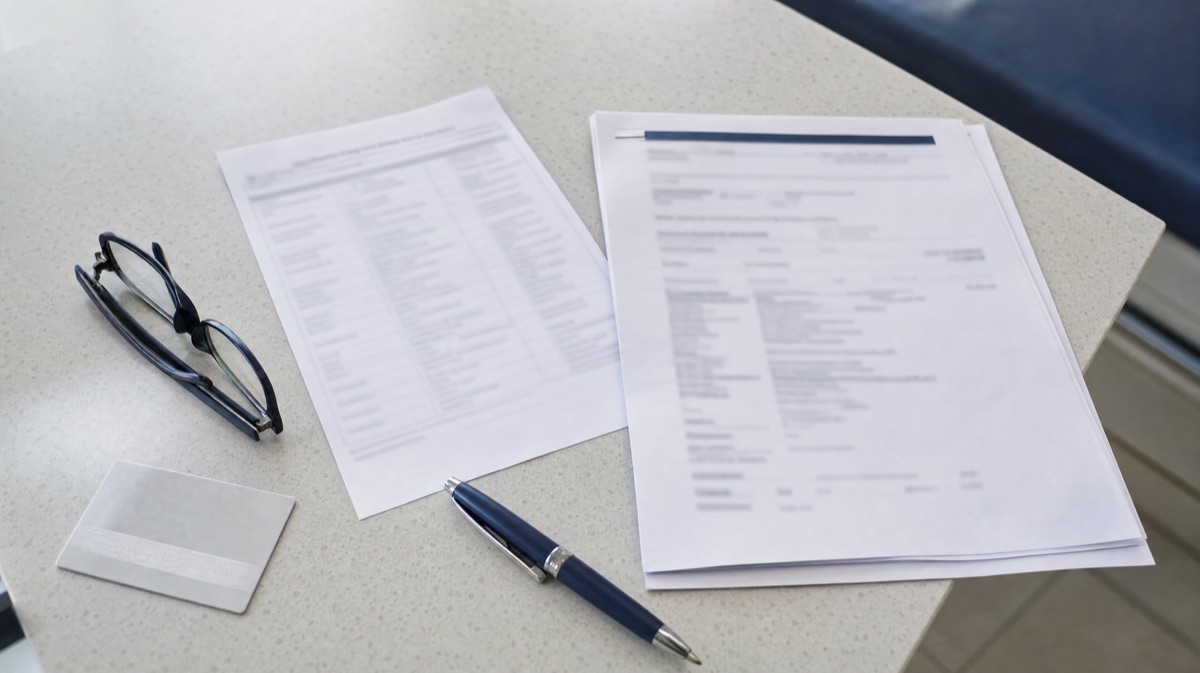 A driver's licence, medication list, medical report and glasses laid out on a clinic counter